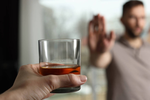 Man refusing to drink whiskey indoors, closeup. Alcohol addiction treatment - Фото, зображення
