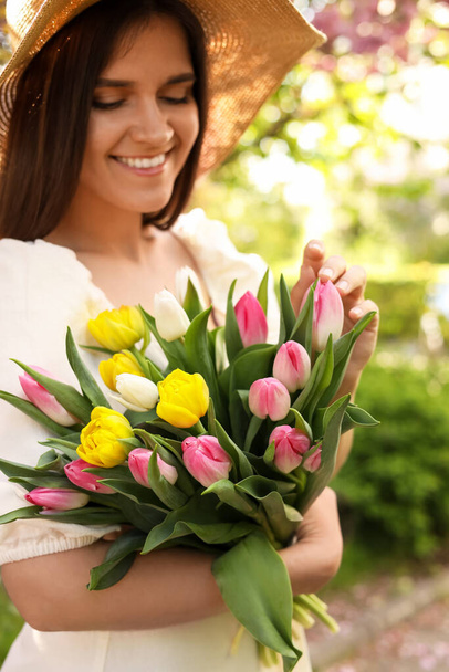 Beautiful young woman with bouquet of tulips in park, focus on flowers - Valokuva, kuva