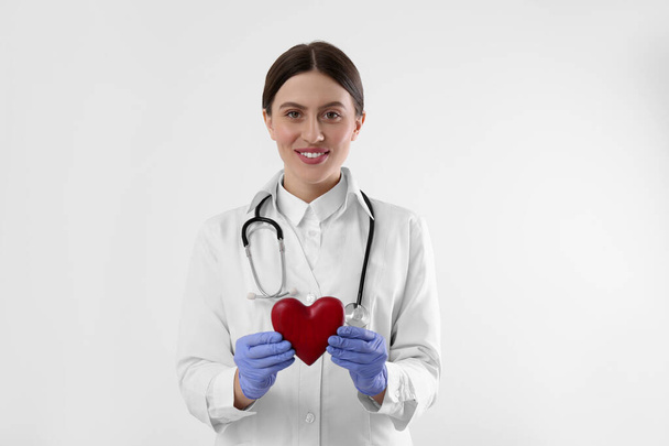 Doctor with stethoscope and red heart on white background. Cardiology concept - Foto, imagen