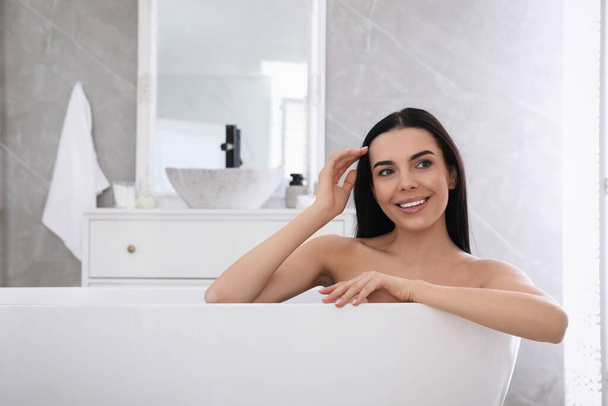 Beautiful young woman relaxing in bathtub at home - Fotoğraf, Görsel