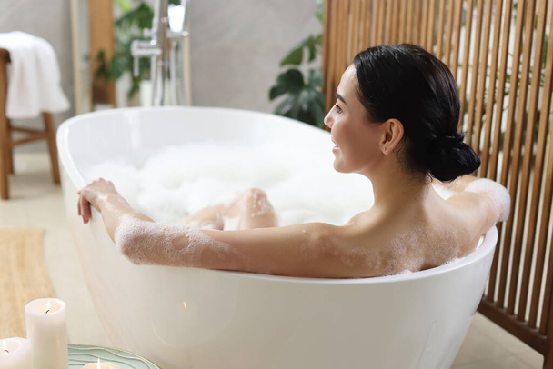 Beautiful young woman taking bubble bath at home - Zdjęcie, obraz
