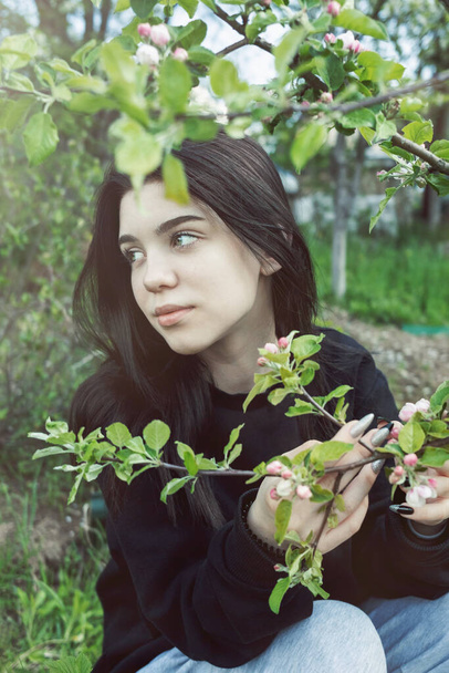 Pretty  teen girl are posing in garden near blossom apple tree with pink flowers. Spring time - Foto, Imagem