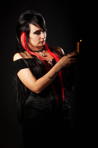 Schöne junge Frau mit roten Haaren, trägt ein langes schwarzes und rotes Flamenco-Spitzenkleid mit schwarzem Korsett. kniend auf dem Boden. isoliert auf weißem Hintergrund. - Foto, Bild