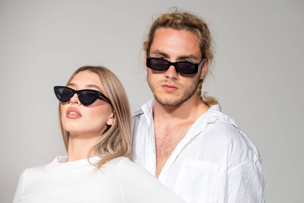 Couple in fashion black sunglasses. Young couple posing with sunglasses. Vogue Style. High fashion look in vogue style. Couple in love on date in formal fashion look. Trendy look. - Zdjęcie, obraz