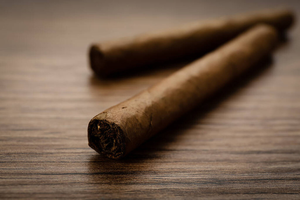 Cigars wrapped in tobacco leaves on wooden table, closeup - Foto, afbeelding