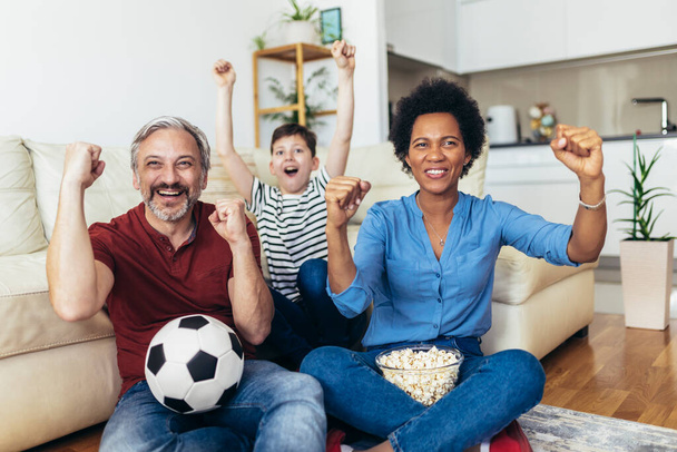 Excited family football fans watching sport tv game celebrating goal together - Foto, imagen