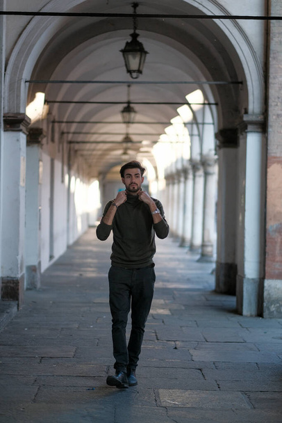Guapo chico italiano pasea bajo las arcadas de Parma. Foto de alta calidad - Foto, imagen