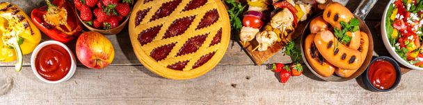 Various picnic barbeque food and drink flatlay. Summer bbq picnic food, assorted grilled meats, kebabs, vegetable, fruit salad, traditional picnic summer pie cake, sandwiches, top view copy space - Photo, Image