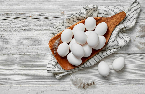 Uova bianche su vassoio di legno su sfondo di legno bianco - Foto, immagini