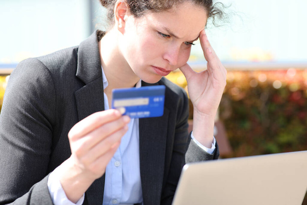 Endişeli iş kadını internetten kredi kartı ve laptopla satın almaktan şikayetçi. - Fotoğraf, Görsel