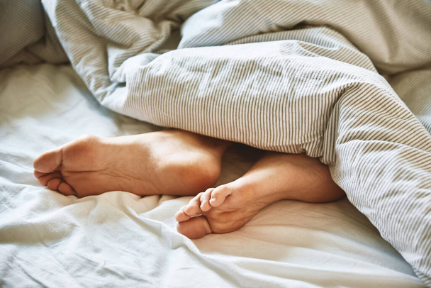 Утренняя концепция, женщина спит в постели, голые женские ноги под одеялом - Фото, изображение