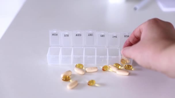 Ręcznie umieścić tabletki do pudełka na pigułki medyczne, tabletki do codziennego zażywania, leki, kapsułki - Materiał filmowy, wideo