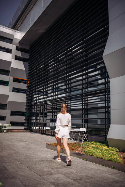Portrait of young modern businesswoman model. Hot beautiful woman in a white suit posing against the backdrop of the street. Fashionable female walks outdoors in sunglasses. - Fotografie, Obrázek