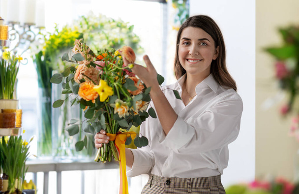 Ευτυχισμένη γυναίκα με πολλά λουλούδια στο ανθοπωλείο - Φωτογραφία, εικόνα