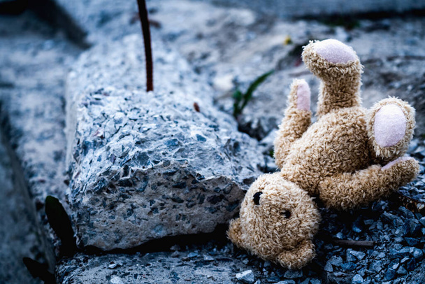 Rusya 'nın Ukrayna' ya karşı savaşı, Rus saldırganlığı, kayıp çocukluk ve geleceğinin sonucu olarak çocukların hayatlarını mahvetti. Çocukların oyuncak ayıları yıkılan binanın beton arka planına karşı.. - Fotoğraf, Görsel