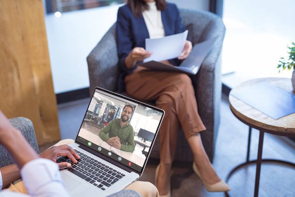 Smiling african american businessman video conferencing with female colleague through laptop. unaltered, office, online, wireless technology, discussion, internet, business, teamwork. - Foto, afbeelding
