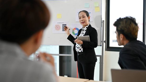 Inteligentna azjatycka kobieta w wieku szef lub kierownik prowadzący prezentację firmy i wyjaśnić cele biznesowe na spotkaniu. - Zdjęcie, obraz