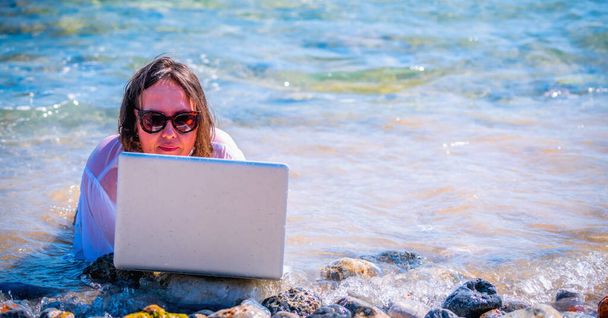 Pracuje wszędzie i zawsze. Bizneswoman pracująca zdalnie, korzystająca z laptopa nad morzem. Kopiuj miejsce na projekt. - Zdjęcie, obraz