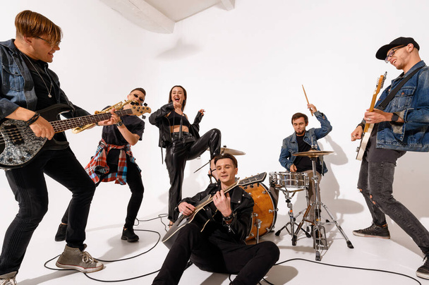 Una giovane rock band di sei persone che suonano e cantano su uno sfondo bianco - Foto, immagini