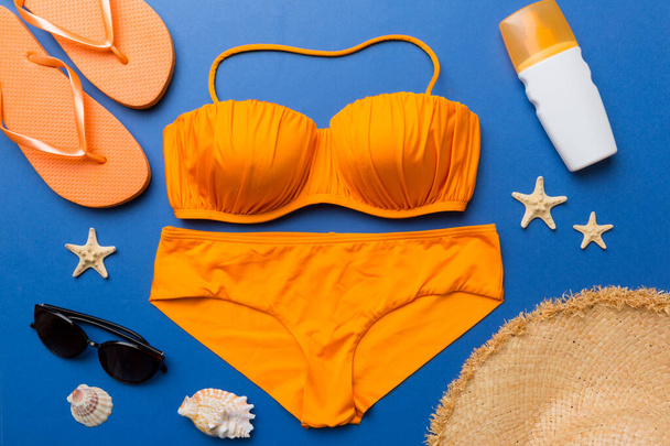 Woman swimwear and beach accessories flat lay top view on colored background Summer travel concept. bikini swimsuit, straw hat and seasheels. Copy space Top view. - Zdjęcie, obraz