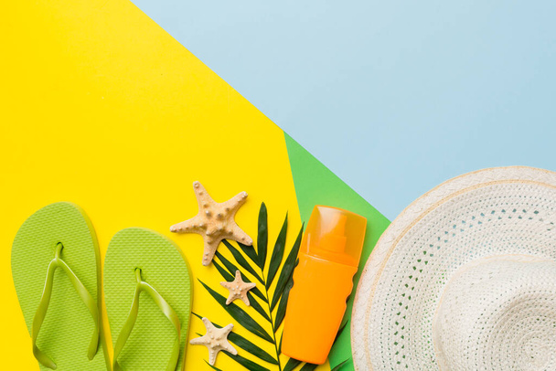 Beach accessories straw hat and seashell on colored table. Summer concept background. - Photo, Image