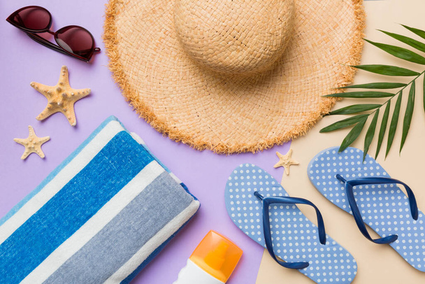 Beach accessories straw hat and seashell on colored table. Summer concept background. - 写真・画像