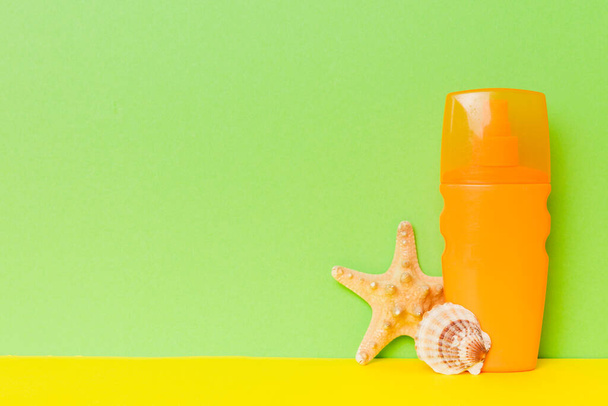 Strandzubehör. Feuchtigkeitscreme Sonnencreme Sonnencreme Flasche für UVB-Hautpflege im Sommer mit Muscheln auf farbigem Hintergrund. Mock up mit Kopierraum. - Foto, Bild
