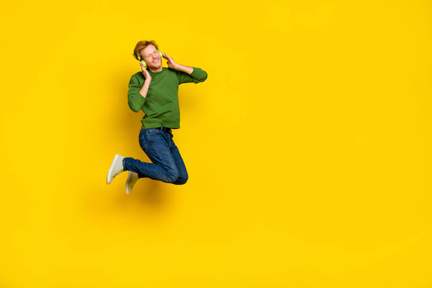 Full length photo of cool dreamy guy dressed sweater earphones enjoying music empty space isolated yellow color background - Fotografie, Obrázek