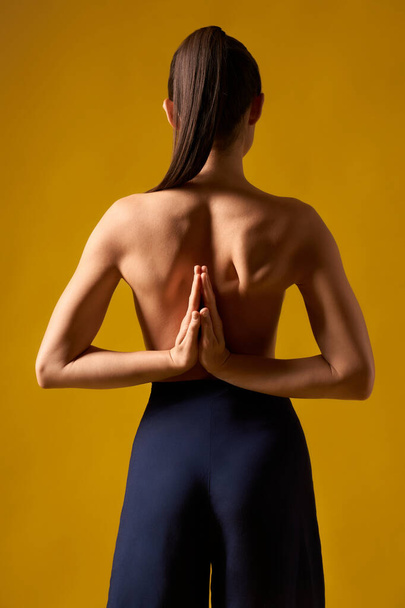 Girl with bare back standing backwards with prayer hands. - Foto, Imagem