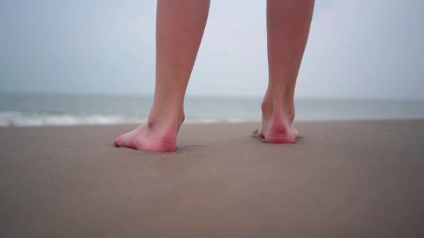Close up of person bare feet walking at tropical beach. People playing barefoot at tropical beach. Having fun jumping in sea water on warm sunny day on seashore. Summer travel and vacation concept - Filmagem, Vídeo