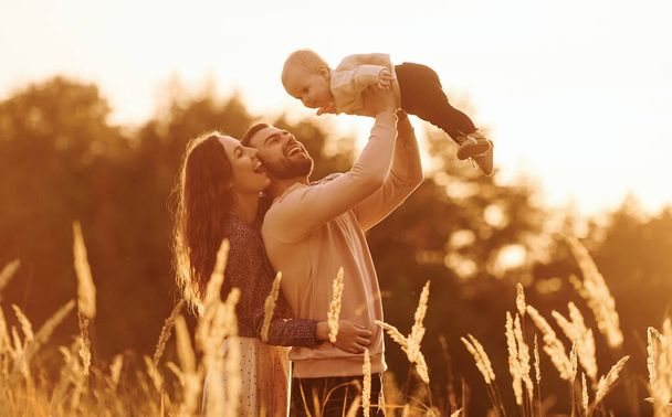 Auringonvalon valaisemana. Onnellinen perhe äiti, perhe ja pieni vauva lepää ulkona. Kaunis aurinkoinen syksyn luonto. - Valokuva, kuva