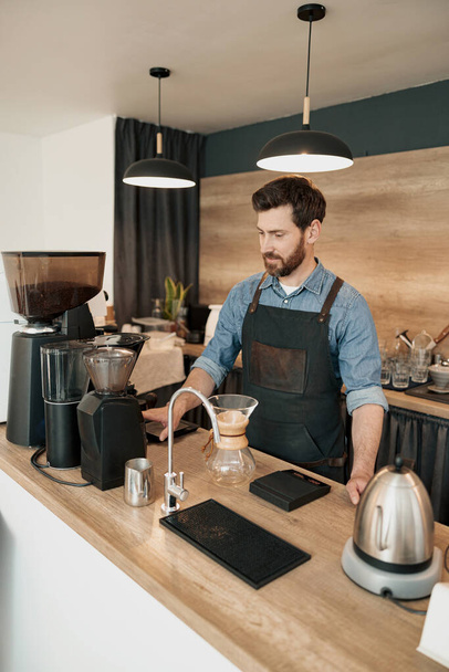 Barista guapo muele granos de café en coffeemachine - Foto, imagen