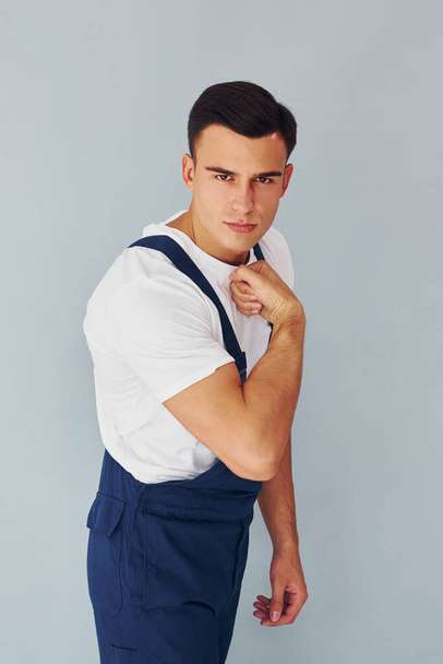 Shows biceps. Ready to work. Male worker in blue uniform standing inside of studio against white background. - Fotografie, Obrázek