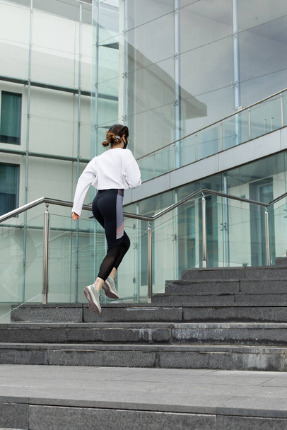 Back view of sporty woman doing hiit workout running on urban outdoor stairs. - Fotó, kép