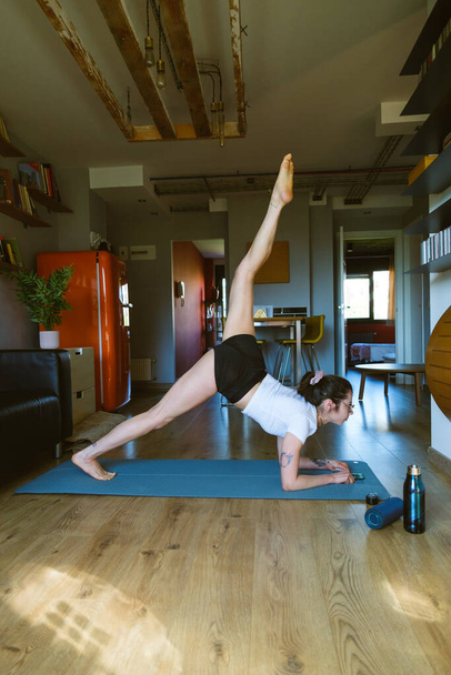 Young fit flexible woman doing yoga at home. Sporty fitness girl exercising indoors. Fitness healthy lifestyle. - Valokuva, kuva