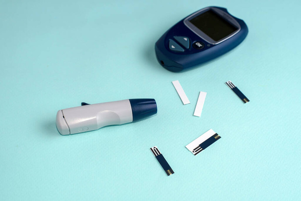 Μετρητής γλυκόζης για τον έλεγχο του διαβήτη χρησιμοποιώντας ως φάρμακο, γλυκαιμία, υγειονομική περίθαλψη και ιατρική έννοια. Μπλε φόντο. - Φωτογραφία, εικόνα