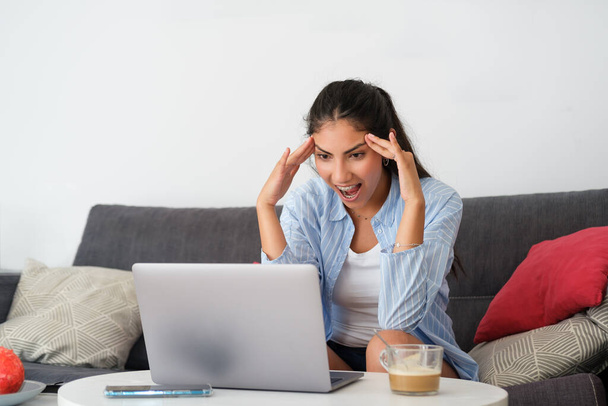 Funny amazed casual latin woman at home looking to her laptop and jawdropping. - Fotoğraf, Görsel