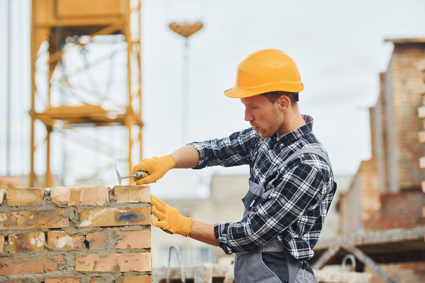 Laying bricks. Construction worker in uniform and safety equipment have job on building. - 写真・画像
