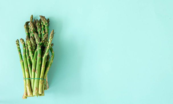 Fresh asparagus plant on blue background, flat lay. - Фото, изображение