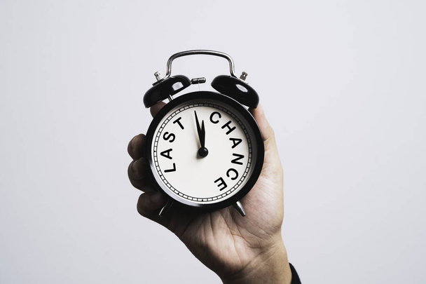 Reloj despertador negro de mano que en el interior última oportunidad de redacción para el concepto de tiempo y oportunidad. - Foto, imagen
