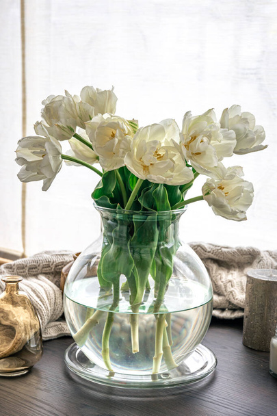 Домашняя композиция с букетом тюльпанов в стеклянной вазе и свечами. - Фото, изображение