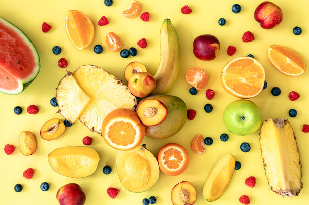 Frutti tropicali e bacche su sfondo giallo, posa piatta. - Foto, immagini