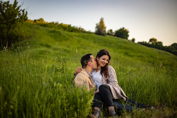 Aimant couple hipster marchant dans le champ, embrassant et tenant la main, étreignant, couché dans l'herbe en été au coucher du soleil. Saint Valentin. - Photo, image