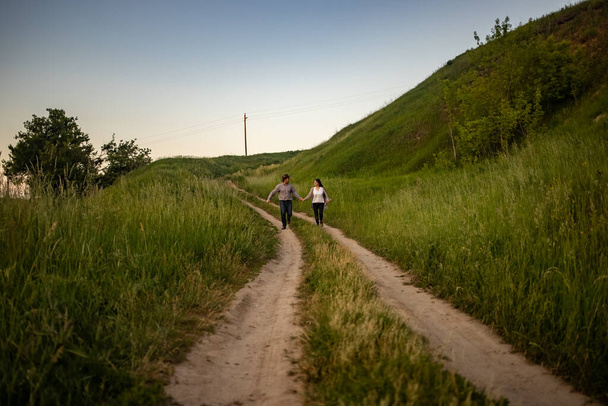 a man and a girl in rustic clothes run along a village road. - Фото, изображение