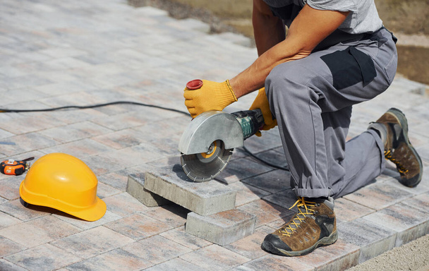 Close up view. Male worker in yellow colored uniform have job with pavement. - Foto, afbeelding