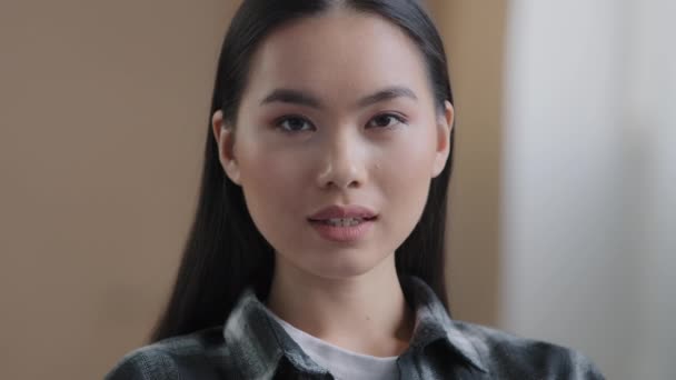 Confident 20s girl 30s asian ethnic woman perfect skin face looking at camera posing alone at home in office millennial korean ethnicity student professional female worker close up front portrait - Materiał filmowy, wideo