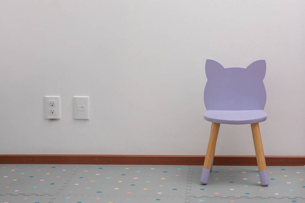 фиолетовый детский стул в офисе с белой стеной и контактами на стене - Фото, изображение