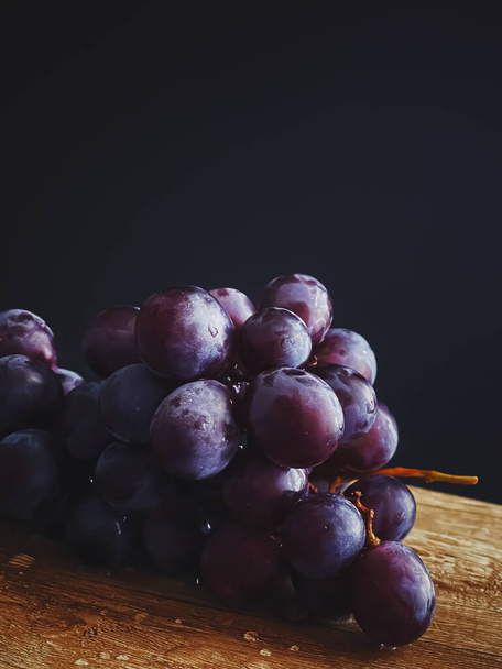 Ripe juicy dark grapes on wooden desk, food and wine, organic fruits concept - 写真・画像
