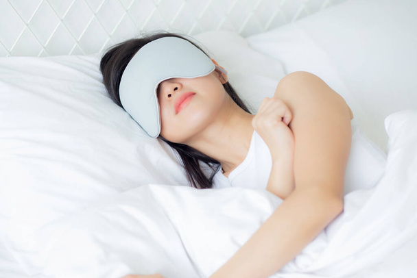 Mooie jonge Aziatische vrouw dragen cover eye en slapen op bed met hoofd op kussen comfort en geluk in de slaapkamer thuis, meisje met ontspanning en vrije tijd voor wellness, lifestyles concept. - Foto, afbeelding