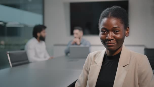 African 30s uśmiechnięty etniczny sukces bizneswoman HR employer lady biracial expert ceo kobieta szef szef lider pracownik patrząc na aparat siedzi przy stole na spotkaniu biznesowym w biurze - Materiał filmowy, wideo